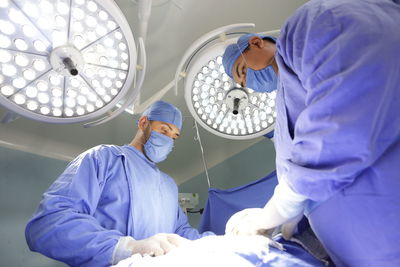 Low angle view of surgeons operating in room