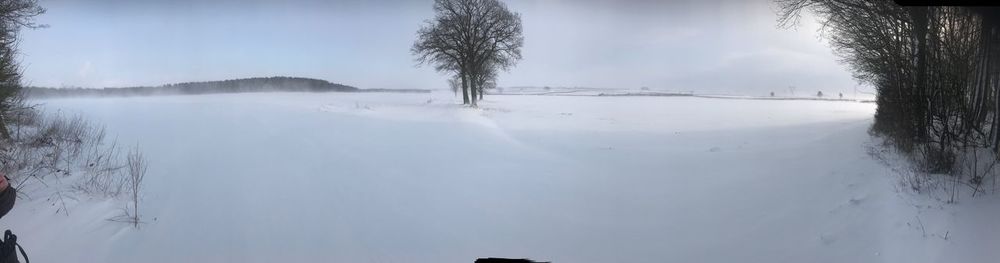 Panoramic view of snow covered landscape against sky