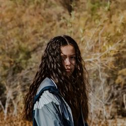 Young woman standing against tree