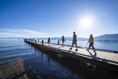 People standing on pier over sea against sky