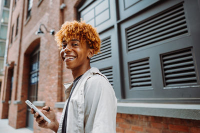 Smiling young adult in city using smartphone