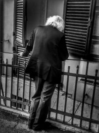 Rear view of man standing by railing in building