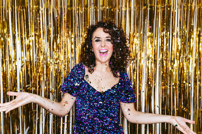 Portrait of smiling woman standing against golden background