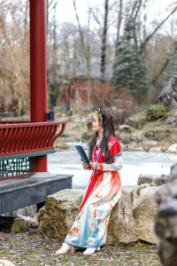 Rear view of young woman standing against trees