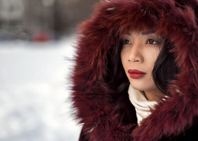 Portrait of young woman wearing red fur cape