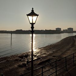 Street light by river against sky