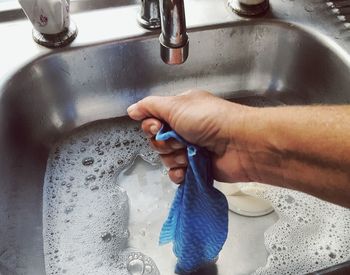 Cropped hand of person washing fabric in sink