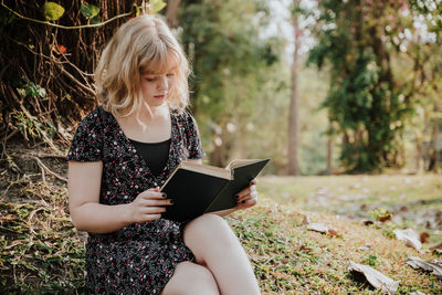 Woman reading book while sitting at park