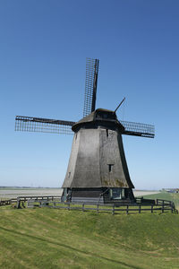 Traditional windmill on field against clear sky