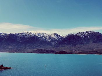 Scenic view of snowcapped mountains by sea against sky