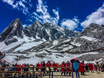 People on snowcapped mountains against sky