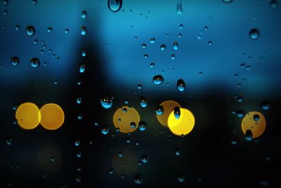 Close-up of raindrops on glass window at dusk