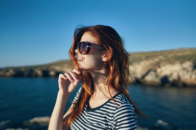 Portrait of young woman wearing sunglasses against sky