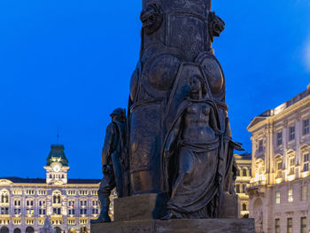 Low angle view of statue of historic building against blue sky