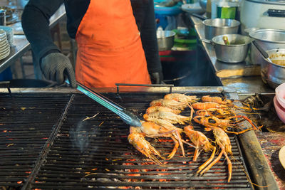 Midsection of man preparing shrimps on barbecue