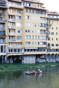 Boat sailing on river against buildings in city