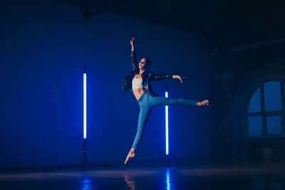 Full length of woman dancing against illuminated lights