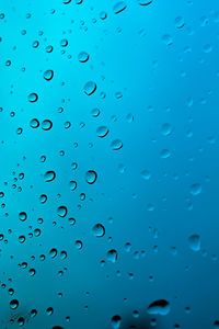Blue sky seen through wet glass window during monsoon
