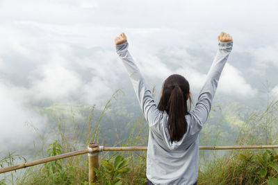 Rear view of woman standing by railing against sky