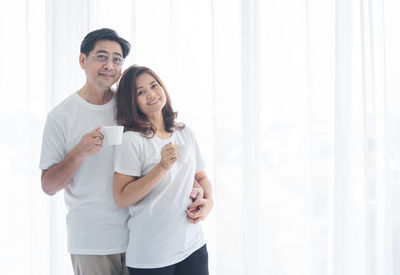 Smiling young couple standing against wall