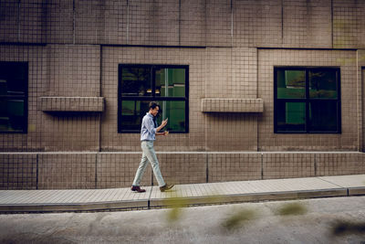 Full length of man walking on street against building