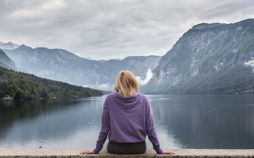 Rear view of woman looking at lake against mountains