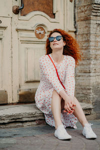 Full length of young woman sitting outdoors