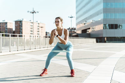 Young woman exercising with resistance band on footpath