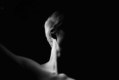 Close-up of shirtless man against black background