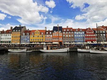 Buildings by river against sky