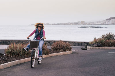 Portrait of mature woman riding bicycle on road against clear sky