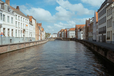 Canal amidst buildings in city against sky