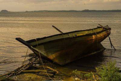 Boat moored on beach against sky