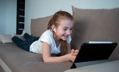 Woman using mobile phone while sitting on sofa at home