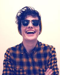 Portrait of young man wearing sunglasses against gray background