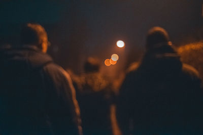 Rear view of couple standing on illuminated city at night