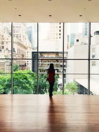 Rear view of woman standing by window