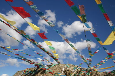 Low angle view of prayer flags hanging against cloudy sky