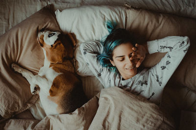 Directly above shot of woman and dog sleeping on bed