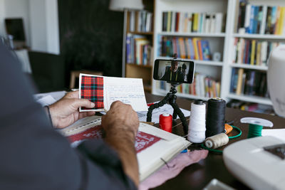 Male tailor explaining about fabric through vlogging on mobile phone at studio