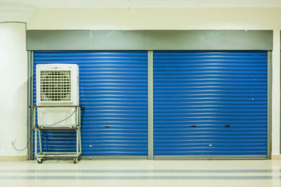 Air conditioner on trolley against closed blue shutters