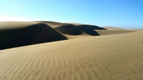 Sand dunes in desert against clear sky