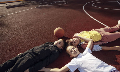 Laid-back laughter, unwinding with children on the basketball court surface, copy space