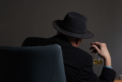 Rear view of man sitting on chair against gray background