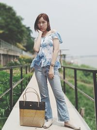 Portrait of woman standing against railing