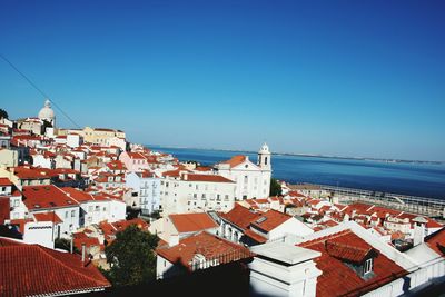 High angle view of town by sea against blue sky