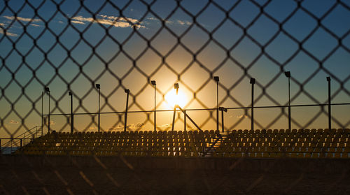 Chainlink fence against sky during sunset