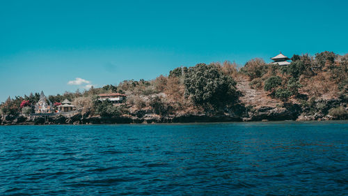 Scenic view of sea by buildings against clear blue sky