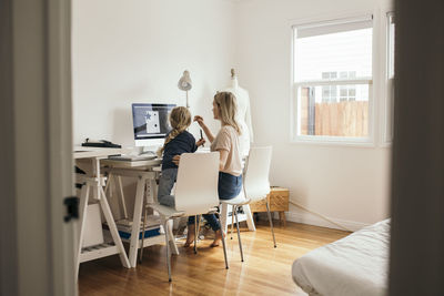 Rear view of design professional with daughter using computer at home