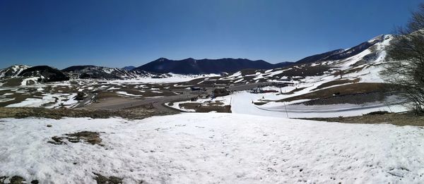 Scenic view of snowcapped mountains against clear blue sky